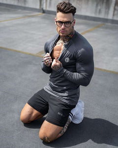 Black men's zipper neck fitness shirt with long sleeves, suitable for gym and sports activities, designed for comfort and performance.