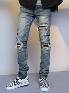 Men's ripped washed blue denim jeans with distressed details and classic fit, showcasing casual men's fashion.